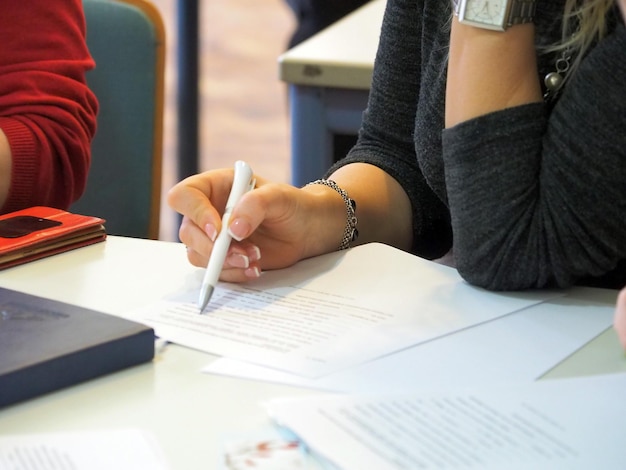 La moitié d'une femme d'affaires écrivant dans le papier sur la table