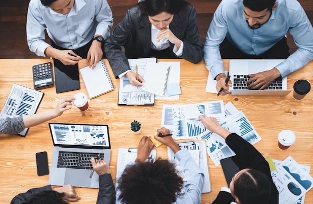 L'équipe d'analystes multiraciaux utilise le logiciel BI Fintech pour analyser les données financières lors de la réunion. Affichage des données du tableau de bord financier avec vue de dessus sur l'écran d'un ordinateur portable avec graphique analysé pour indication marketing Concord