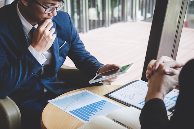 Une section médiane d'hommes d'affaires utilisant une tablette numérique assis avec un collègue à table